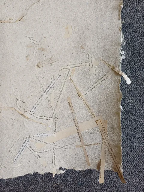 Close-up of a sheet with strips of printed text pressed into the surface