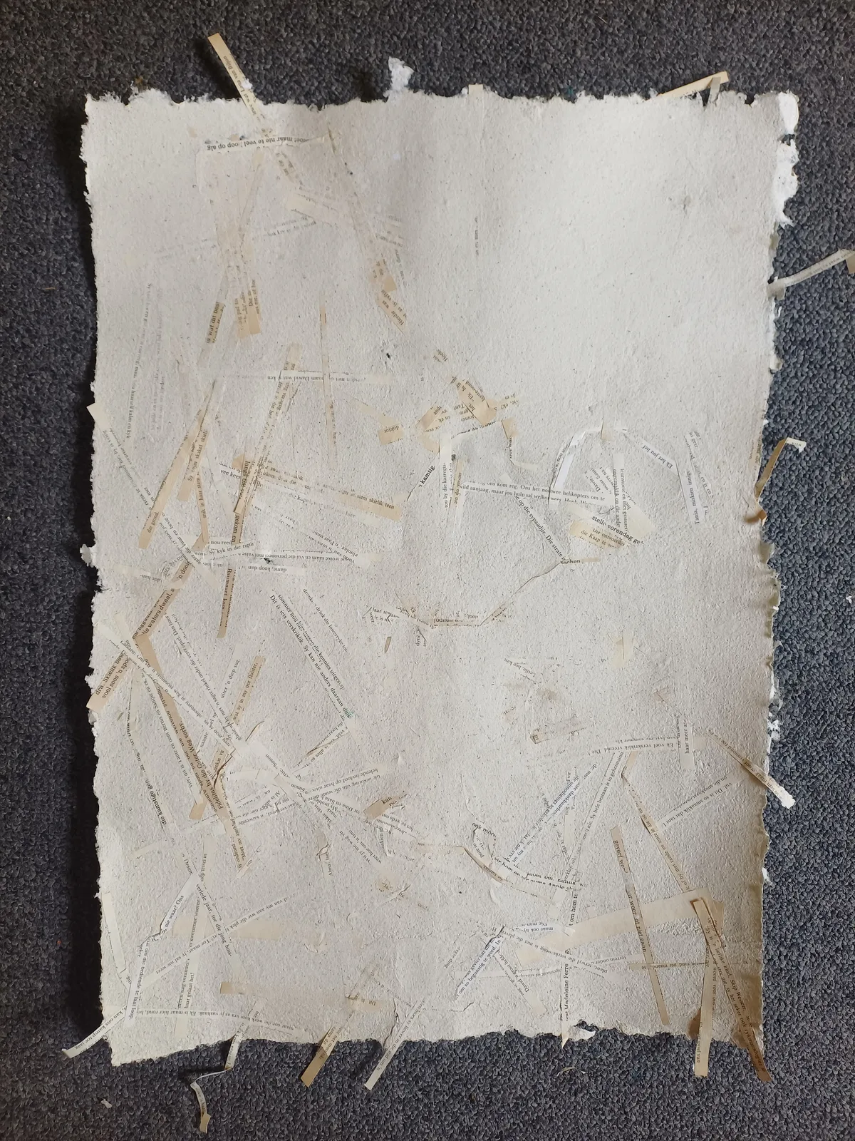 An A4 sheet of handmade paper with straw and plant fibre set into the surface